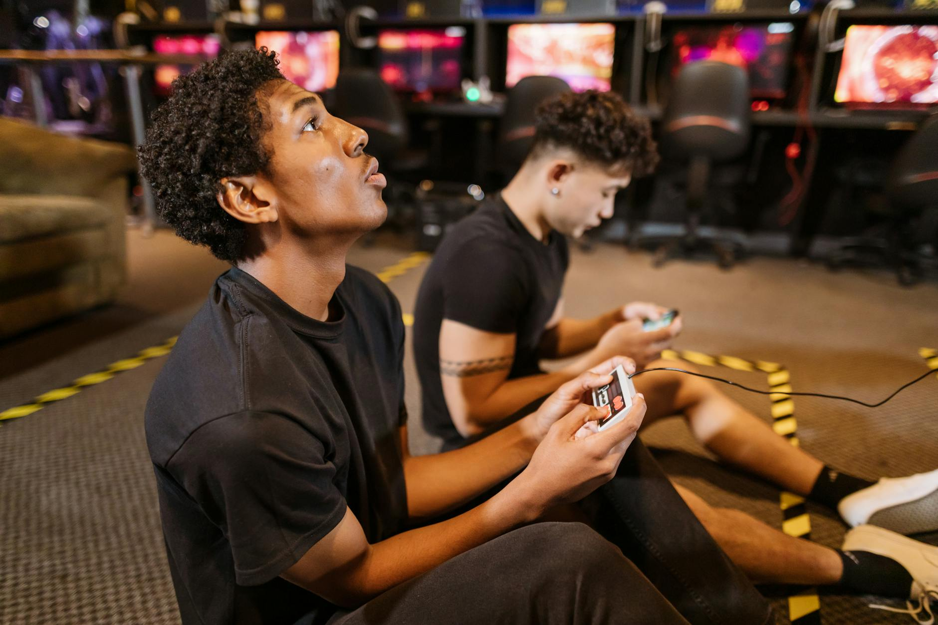 two men sitting on the floor while playing a video game
